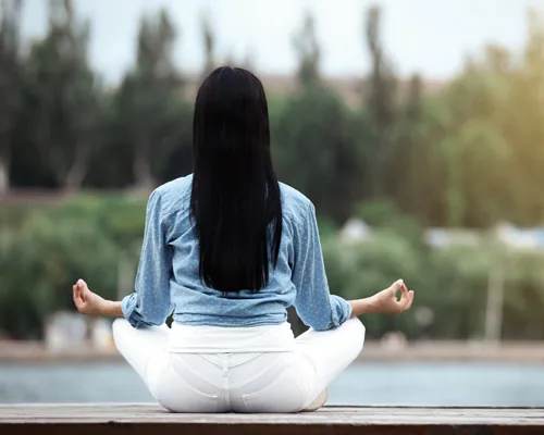 Woman meditating outdoors, representative image of the open yoga deck amenity at Vaishnavi Houdini